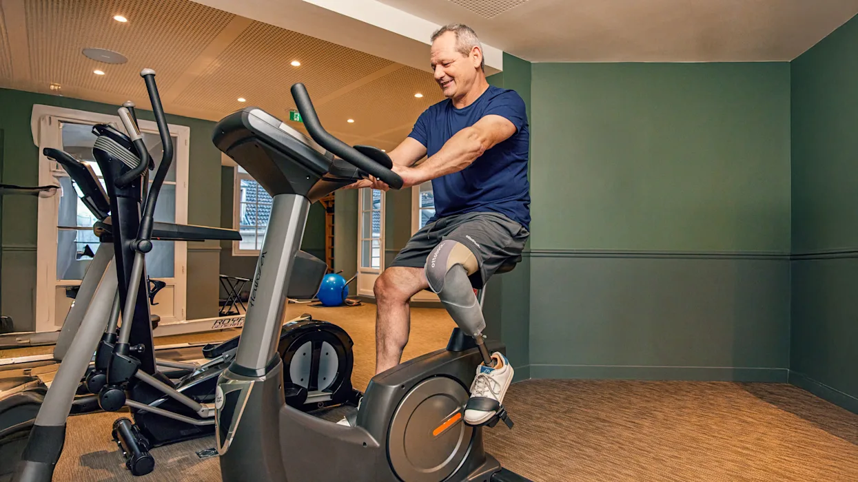 A lower limb transtibial amputee riding a stationary bike in a workout facility