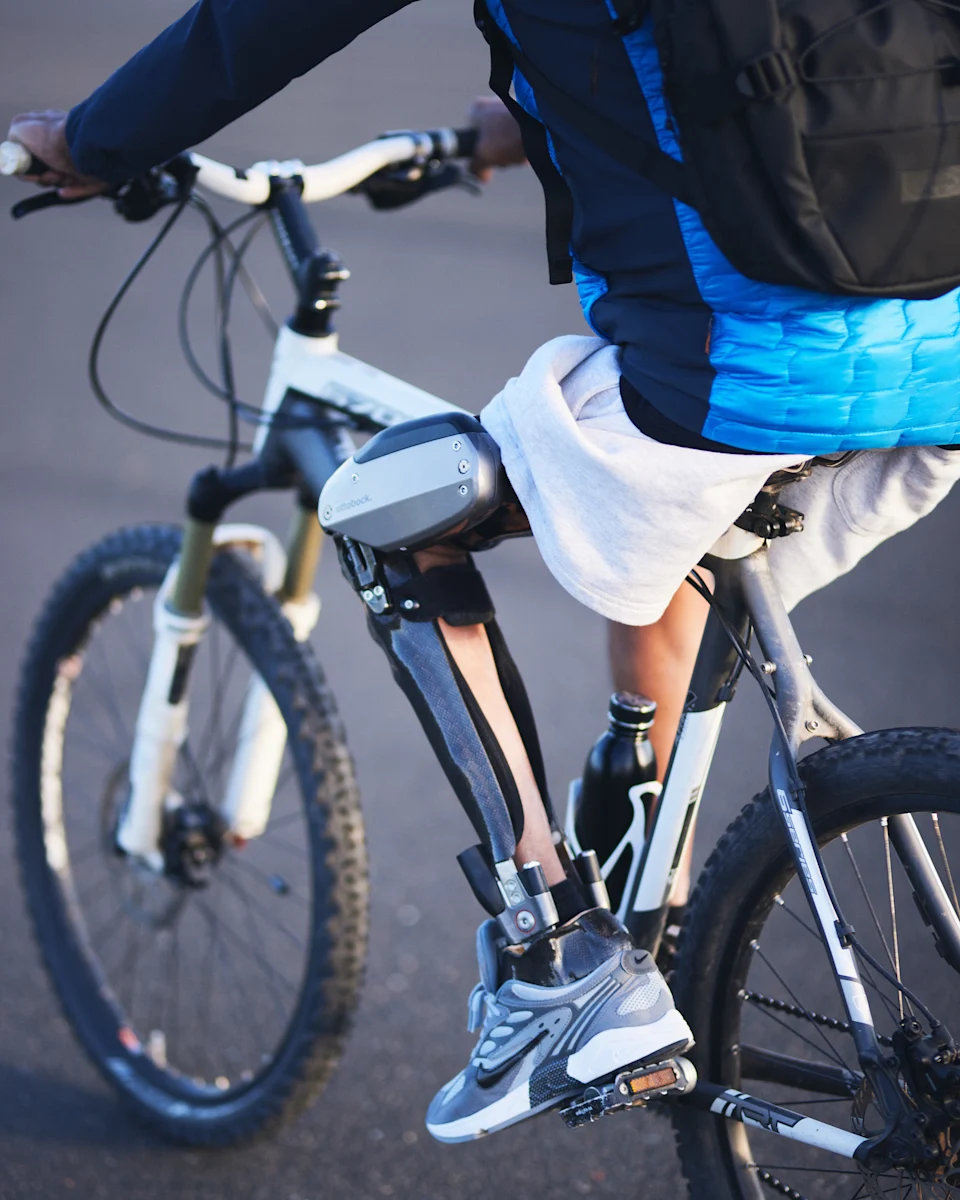 Un usuario de la órtesis de pie de rodilla y tobillo montando su bicicleta con la ayuda del C-Brace de Ottobock