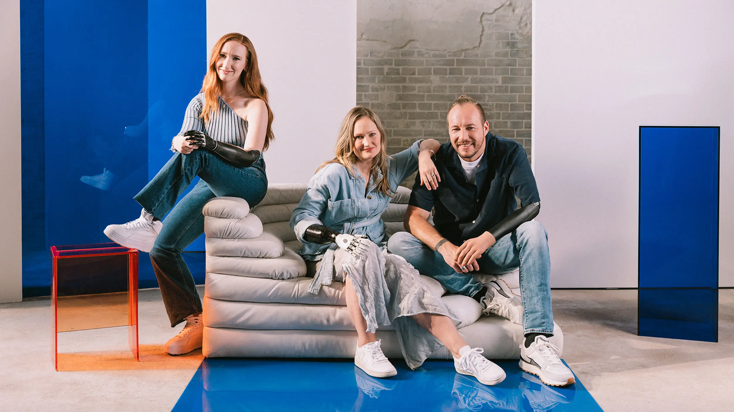 Prosthetic arm users of varying amputation levels gathered on a couch