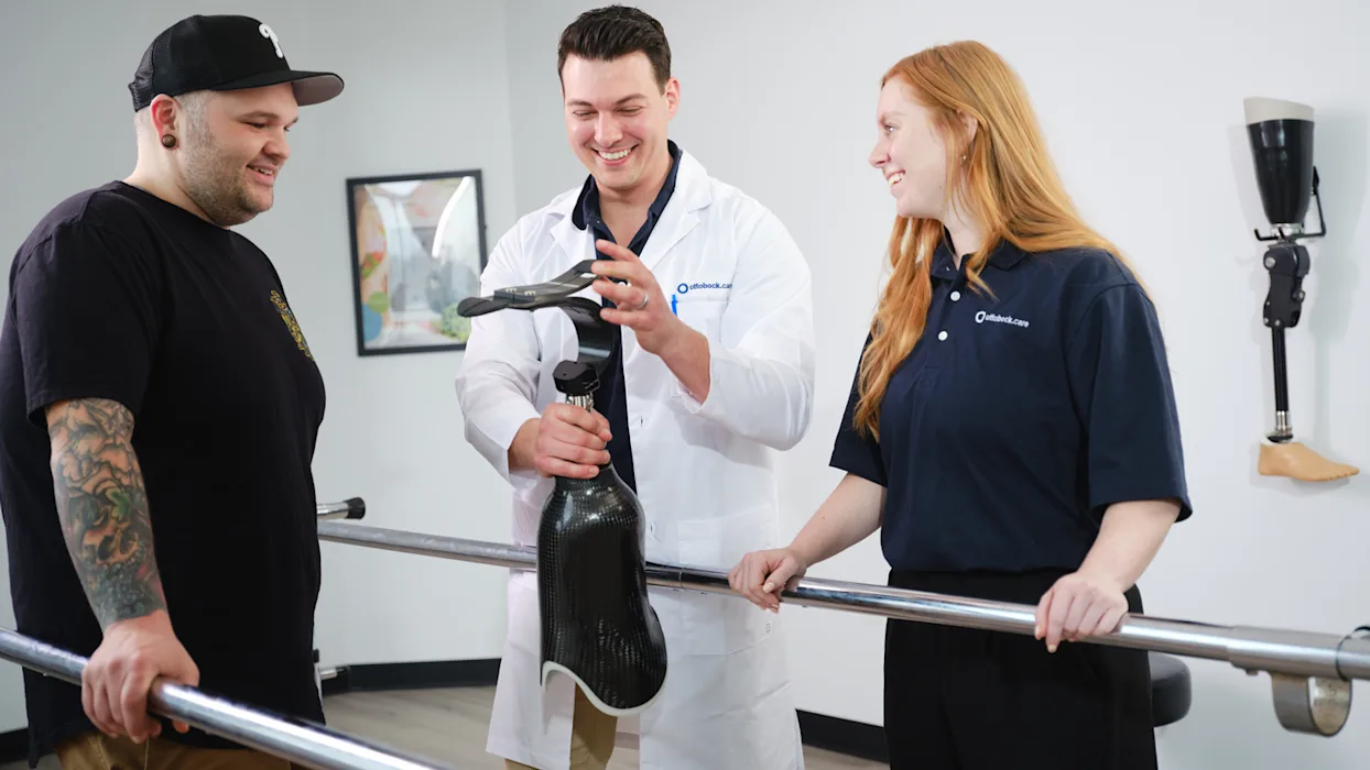 Two Ottobock.care employees reviewing a prosthetic running leg with a lower limb amputee patient
