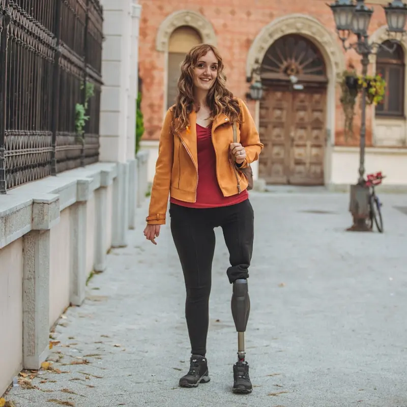 Un amputado de una extremidad inferior posando con una chaqueta naranja para representar el Mes de Concientización sobre la Pérdida de Extremidades