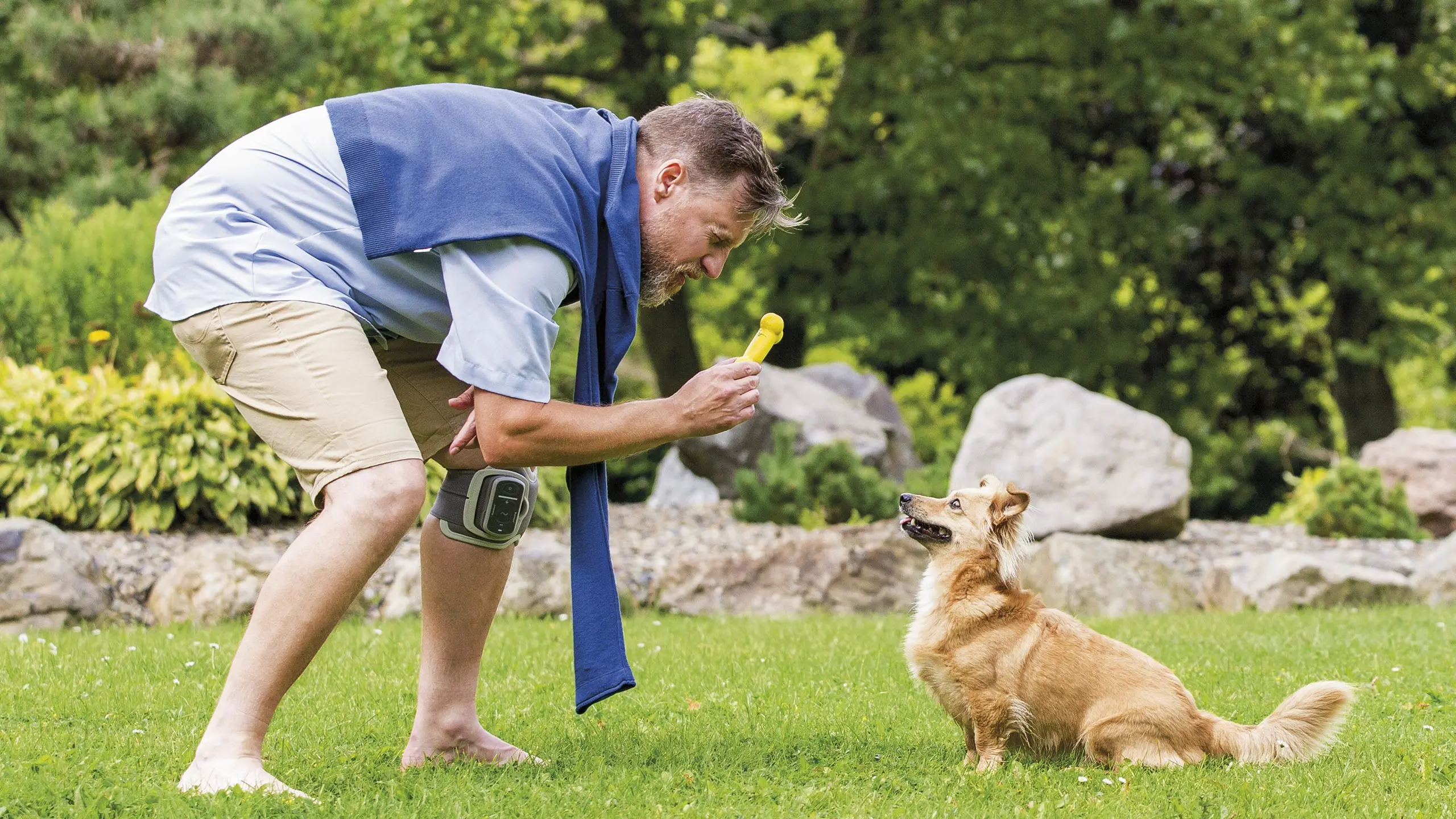 Un paziende che indossa il dispositivo L300 Go gioca a piedi nudi sull'erba con il suo cane