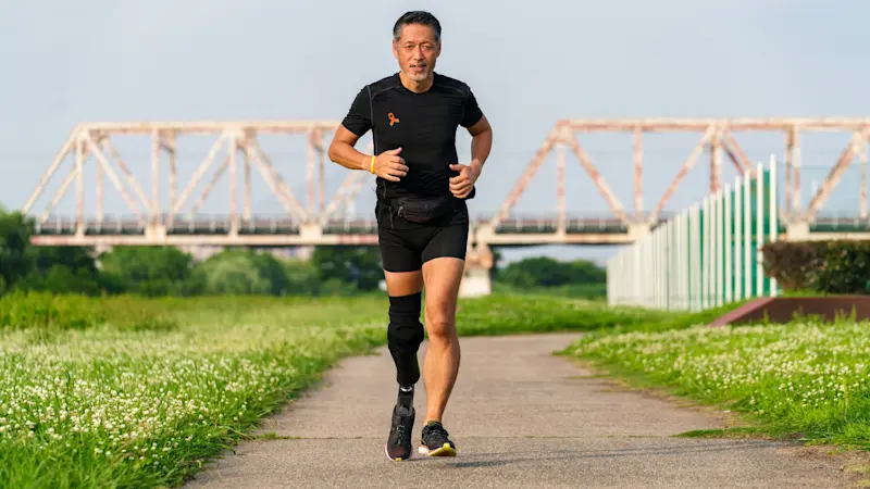 Una persona con diferencia de extremidad trotando en una pista al aire libre