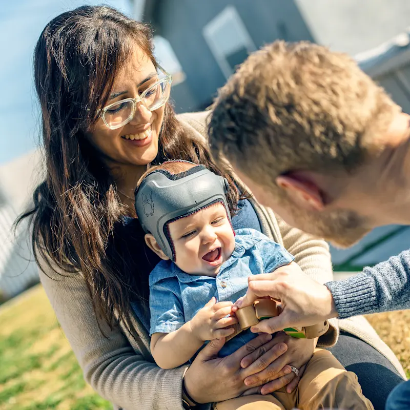 Parents playing with their child with the Ottobock MyCRO Band helmet