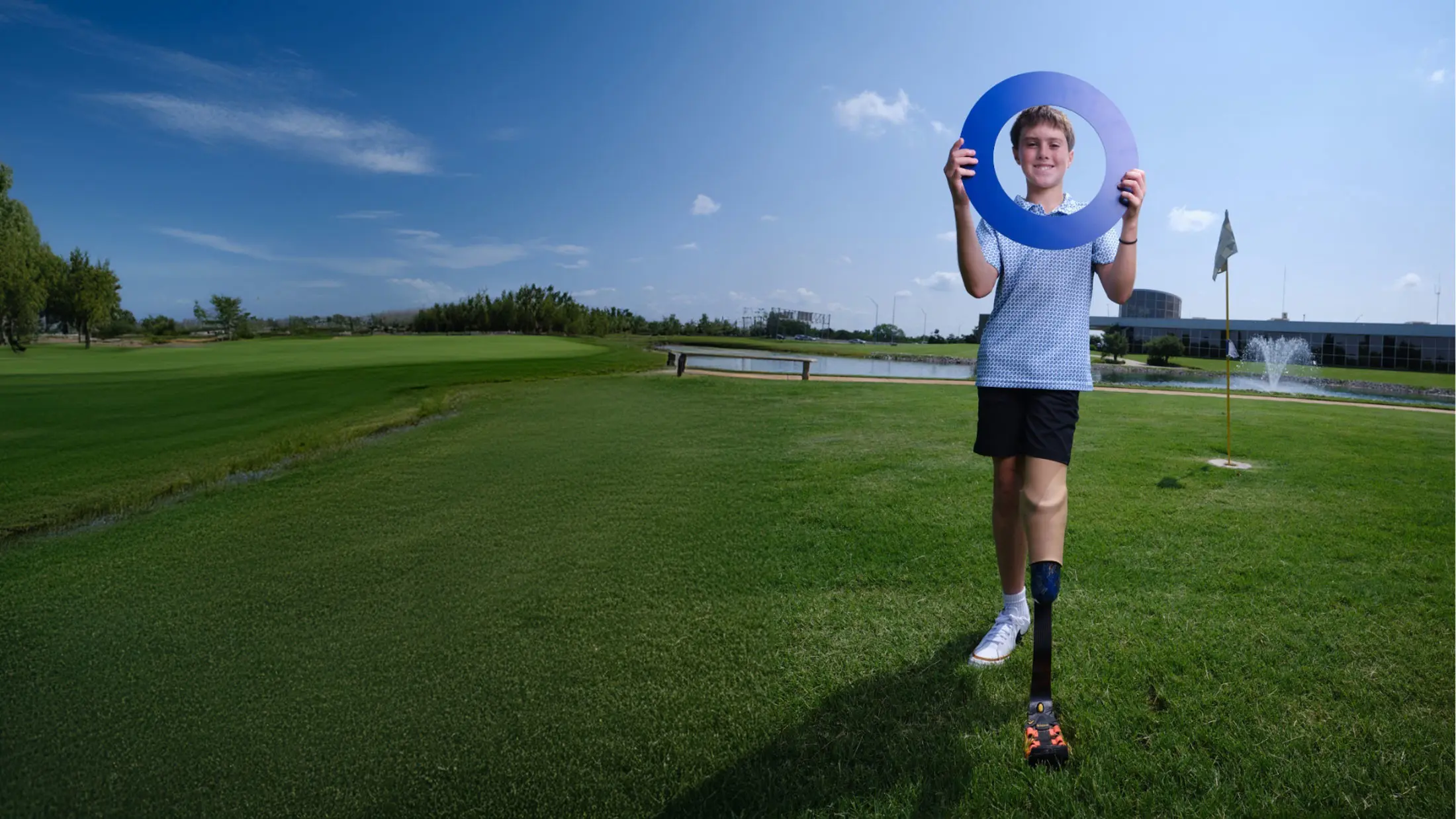 A lower limb prosthetic leg user holding the Ottobock Care logo standing in a golf course
