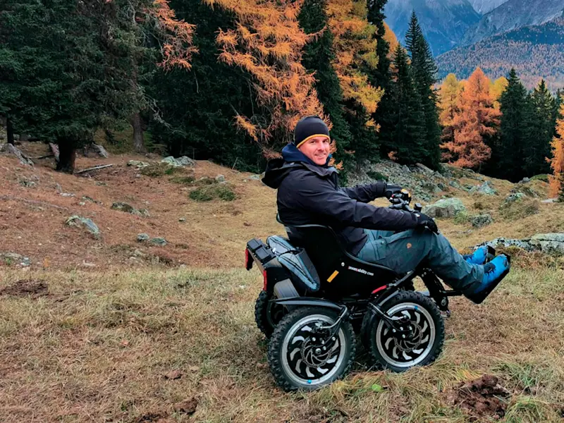 Un uomo a bordo del fuoristrada elettrico Zoom Uphill osserva il panorama autunnale in montagna