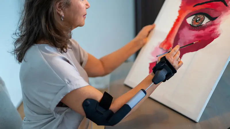 Una donna dipinge su tela utilizzando una ortesi STIL al braccio