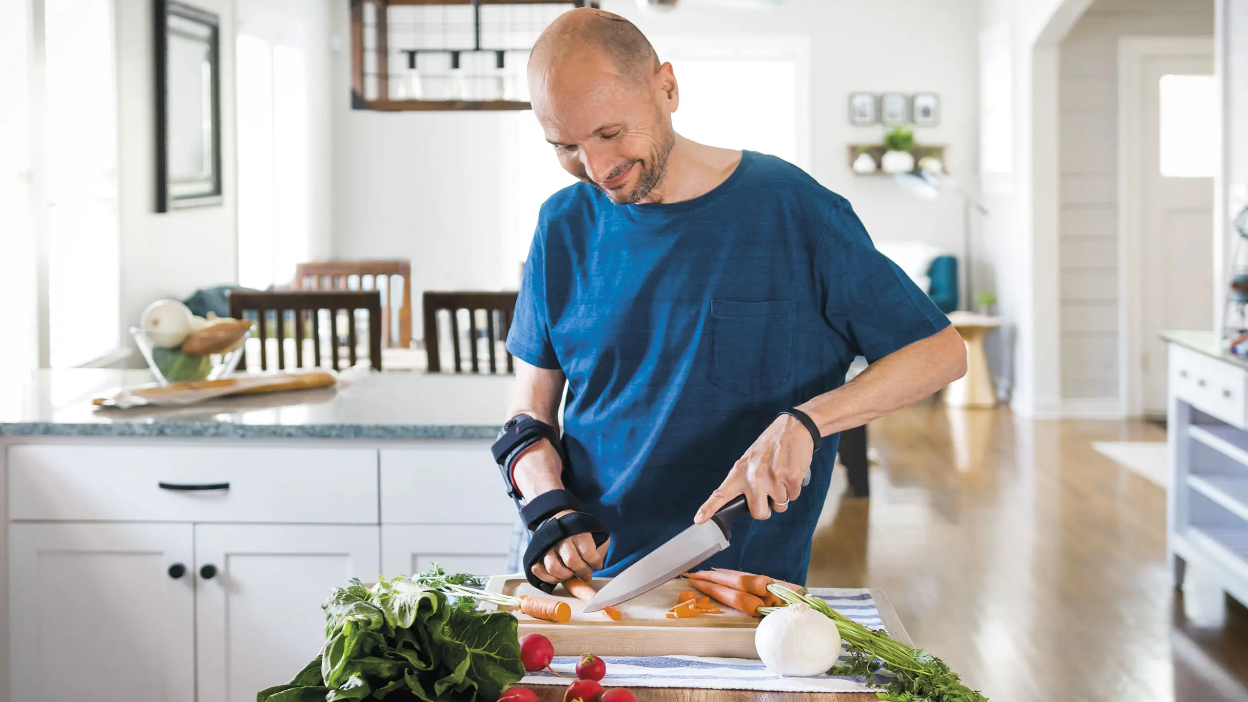 Un paziente con ortesi neurologica Manu Neurexa Plus è impegnato in cucina a tagliare le verdure