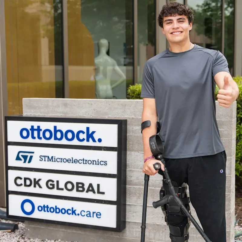 A man with a neuromobility condition posing in front of the Ottobock Care facility's sign