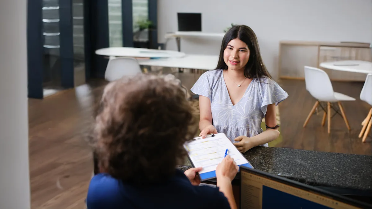 A front desk admin handing a patient with a prosthetic arm the paperwork to fill out before their appointment