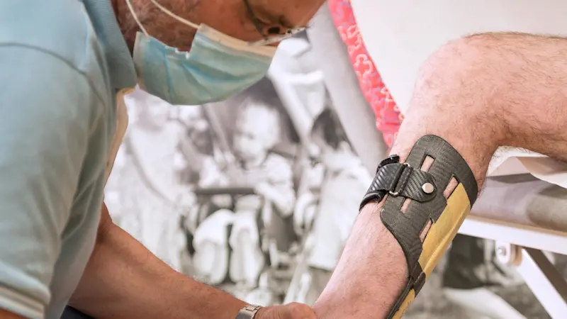 Un tecnico ortopedico regola un ortesi AFO Botter sulla gamba di un paziente in un centro Ottobock.care