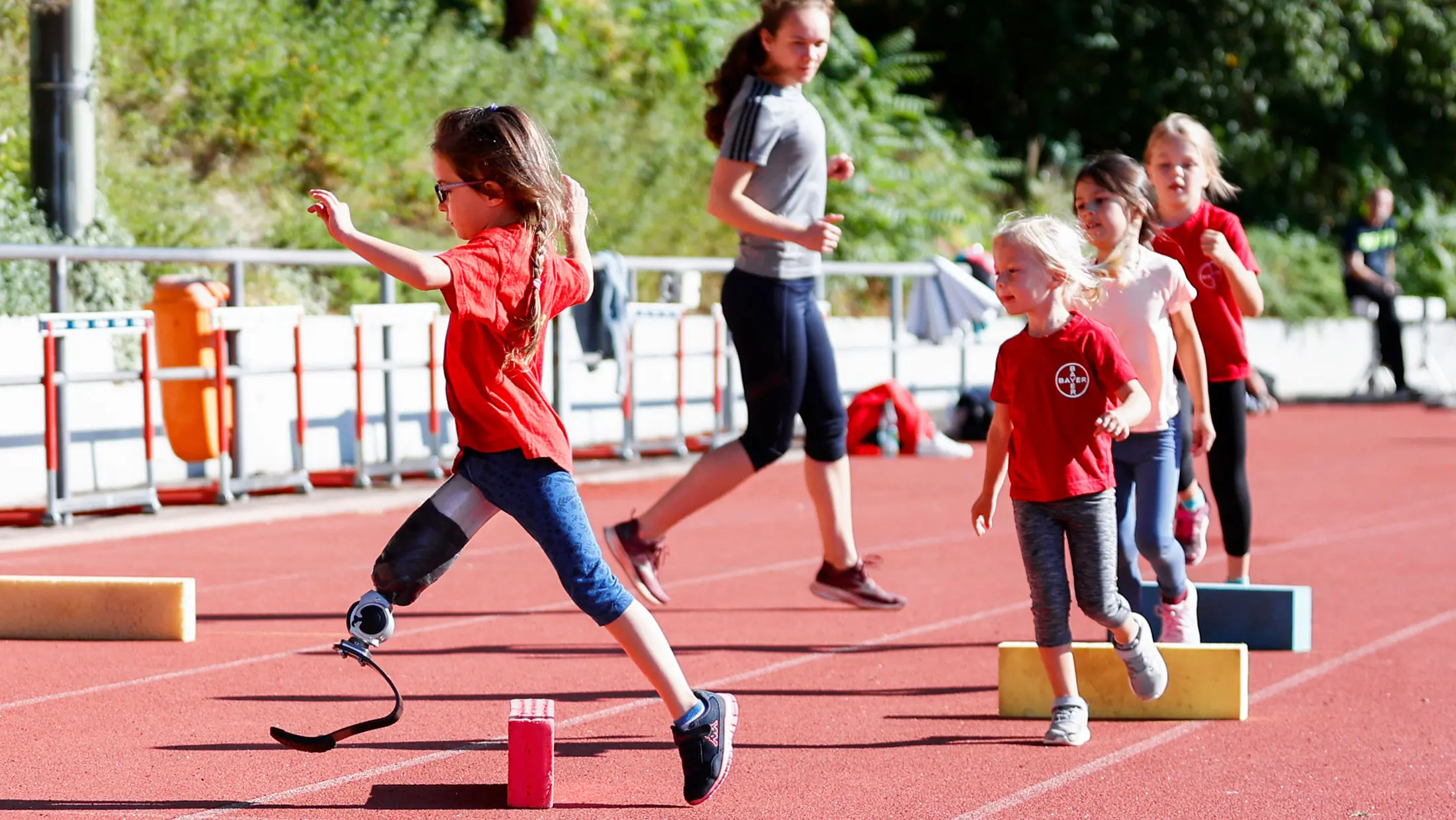 Several children and a pediatric amputee running through obstacles on an outdoor course