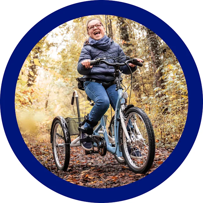 Una bambina sorride in mezzo al bosco mentre si trova in sella al suo triciclo Momo