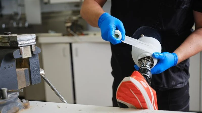 Técnico protésico que envuelve la fibra de vidrio alrededor del zócalo para la prueba