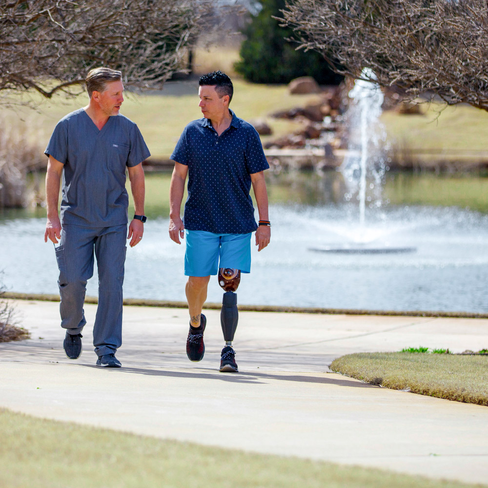 Un ortopedista protésico certificado caminando por un sendero al aire libre a lo largo de un estanque