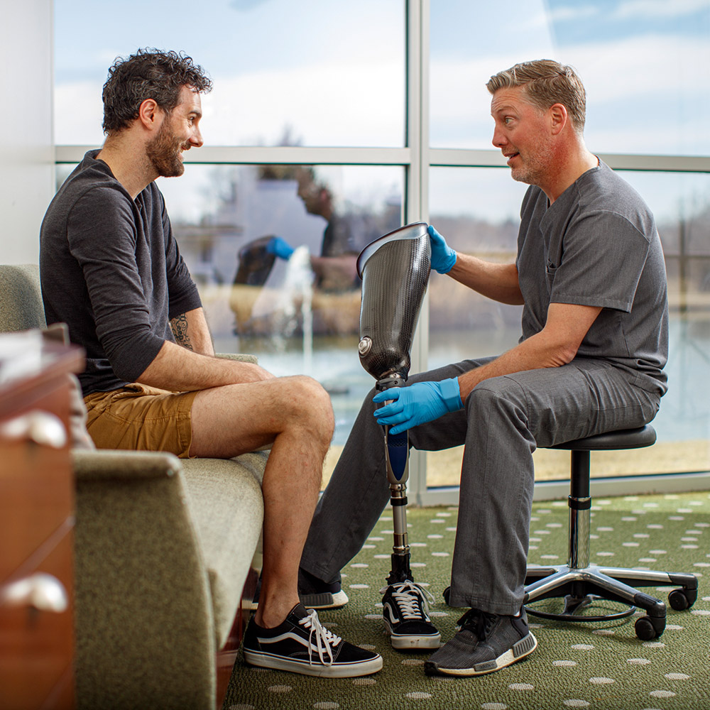 Un CPO consultando con un paciente mientras muestra un encaje protésico personalizado