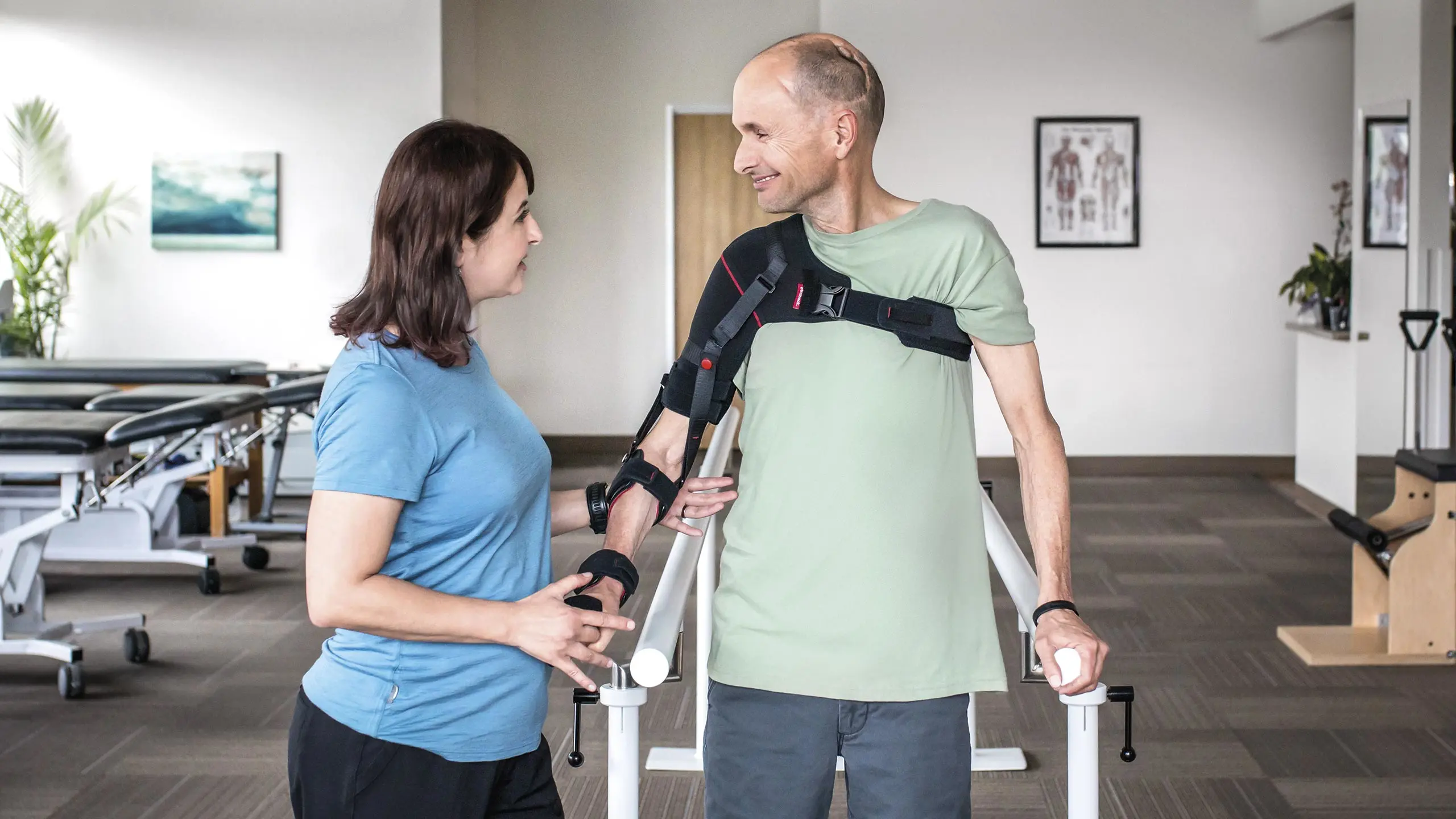 Un paziente si esercita in palestra sotto la supervisione della fisioterapista mentre indossa le due ortesi neurologiche Manu Neurexa e Omo Neurexa combinate