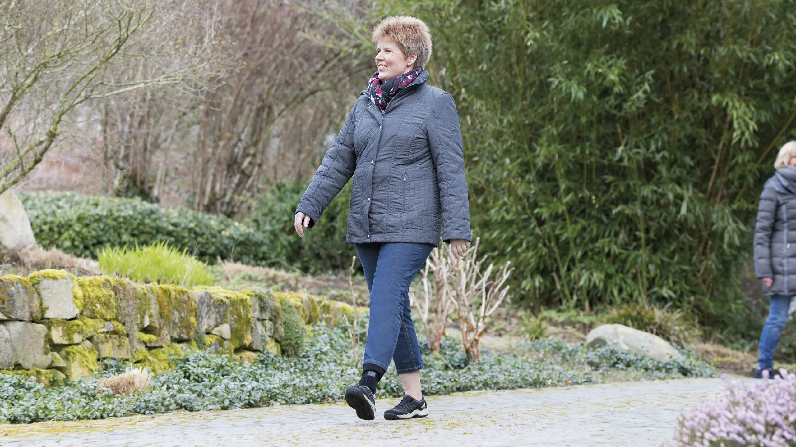 Una donna che passeggia in un parco indossando l'ortesi caviglia-piede neurologica GoOn