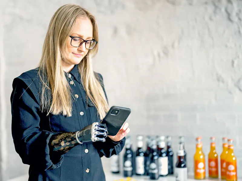 An upper extremity amputee scrolling on her smartphone while holding it up with her prosthetic arm