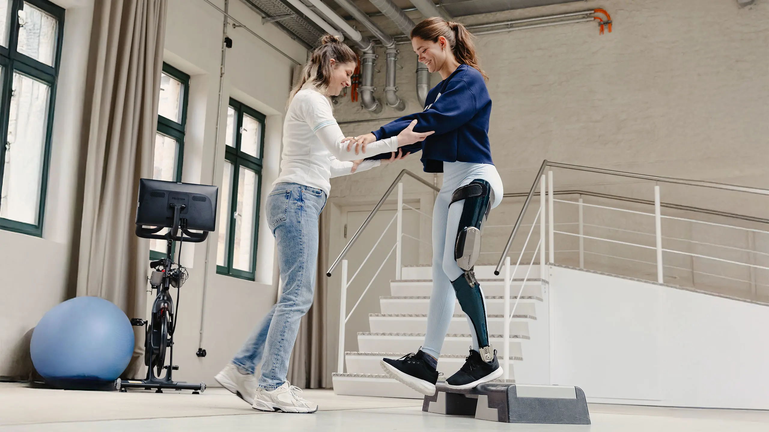 Una fisioterapista Ottobock.care aiuta una ragazza con C-Brace ad eseguire esercizi su rampe e scale per imparare ad utilizzare l'ortesi