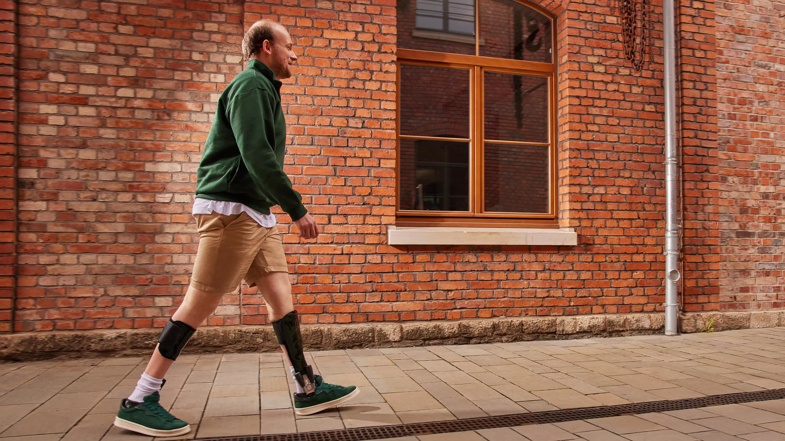 Un paziente con ortesi Nexgear Tango cammina lungo una strada di mattoni rossi