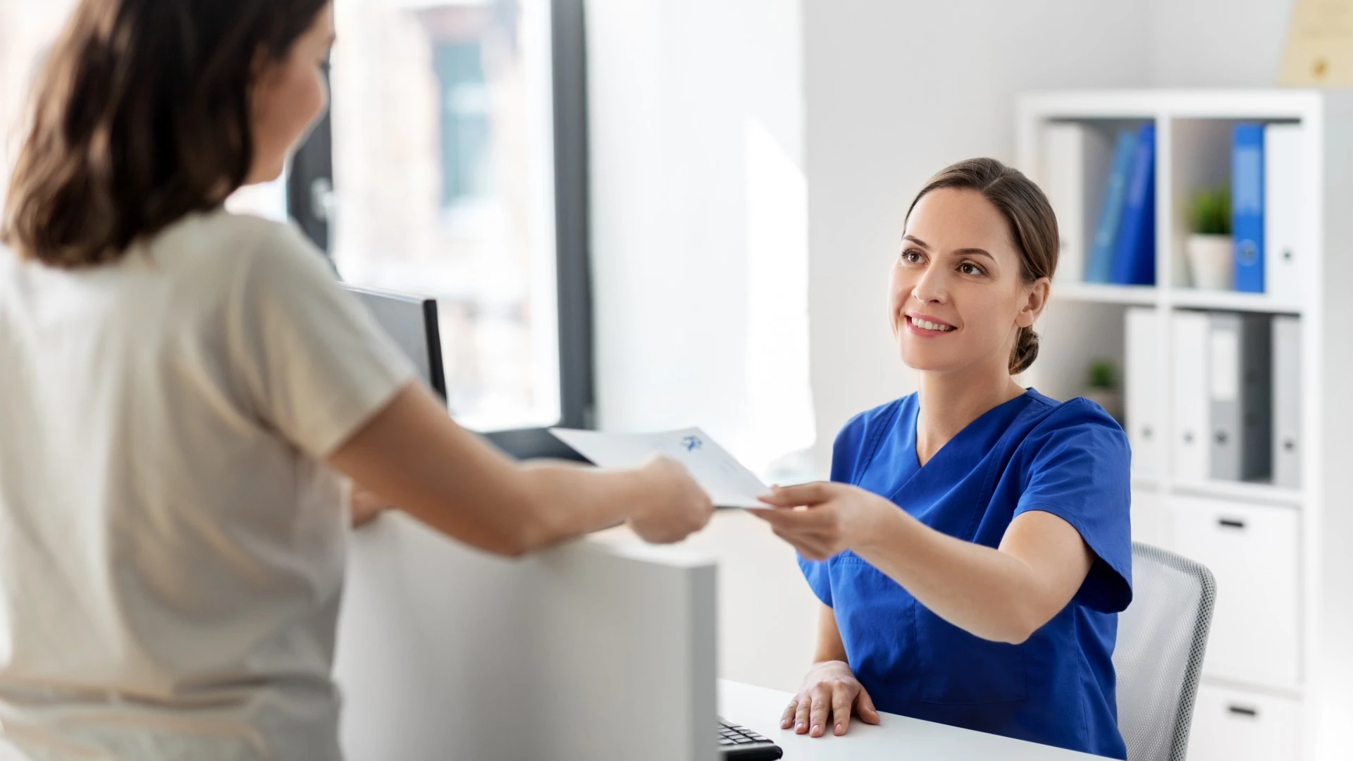 A patient giving medical documents to a healthcare administrator