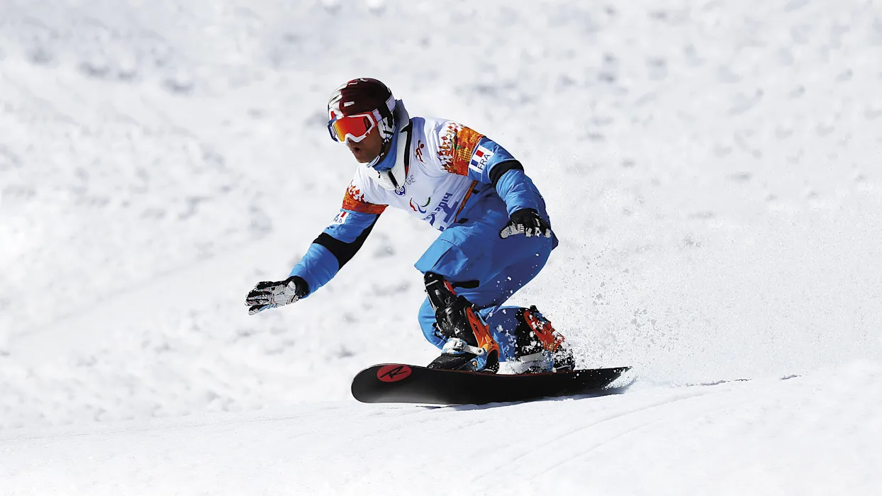 Uno snowboarder con piede protesico ProCarve scende sulla neve piegato sulla tavola