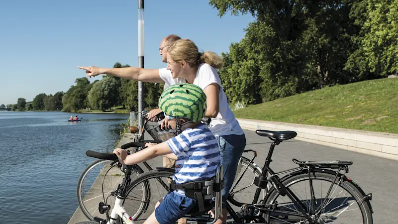 Un bambino su una bicicletta Momo con le rotelline sosta a bordo lago