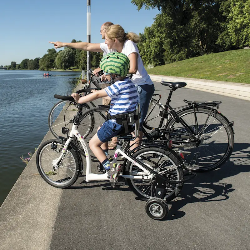 Un bambino su una bicicletta Momo con le rotelline sosta a bordo lago