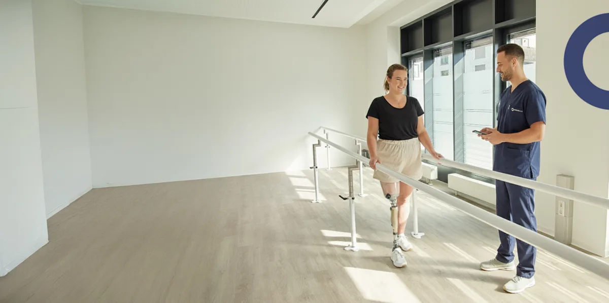 A prosthetic user patient conducting gait training in an Ottobock Care facility while being monitored by a Certified Prosthetist Orthotist