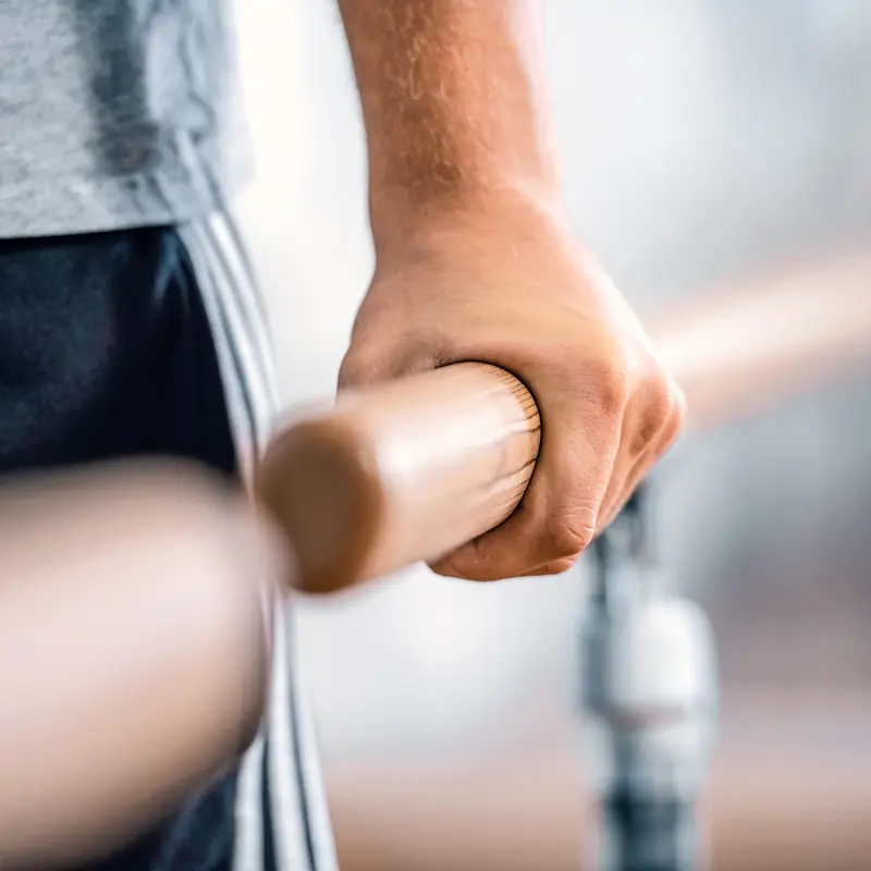 A hand grasping the parallel bars in a clinic setting for prosthetic gait training