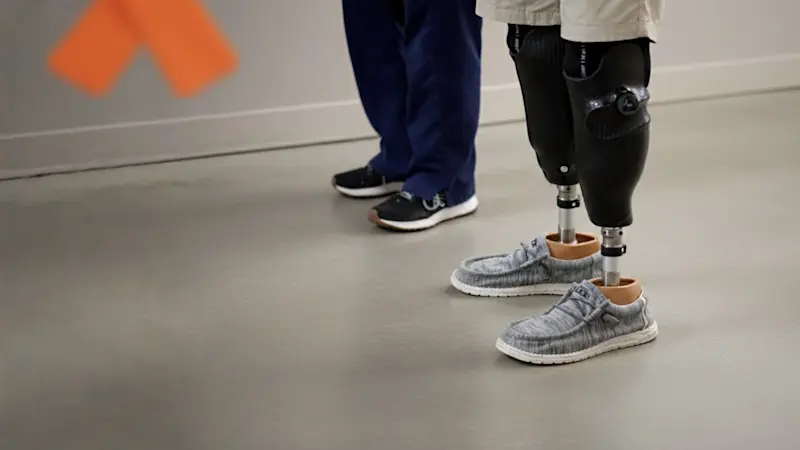 Un usuario de pierna biónica bilateral acompañado por un médico 