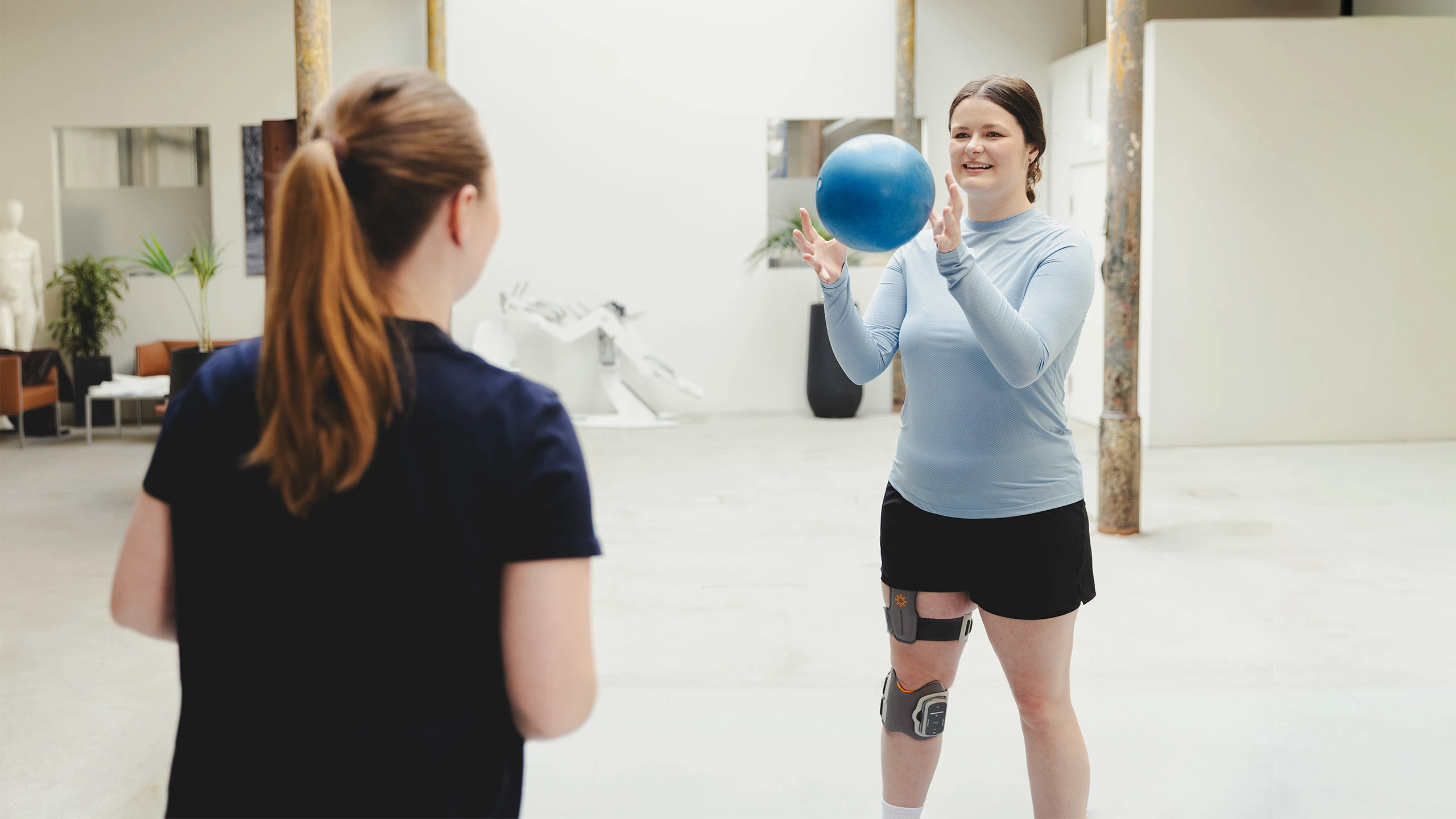 Una paziente con il sistema L300 Go si allena con la palla medica in palestra ssistita da una fisioterapista