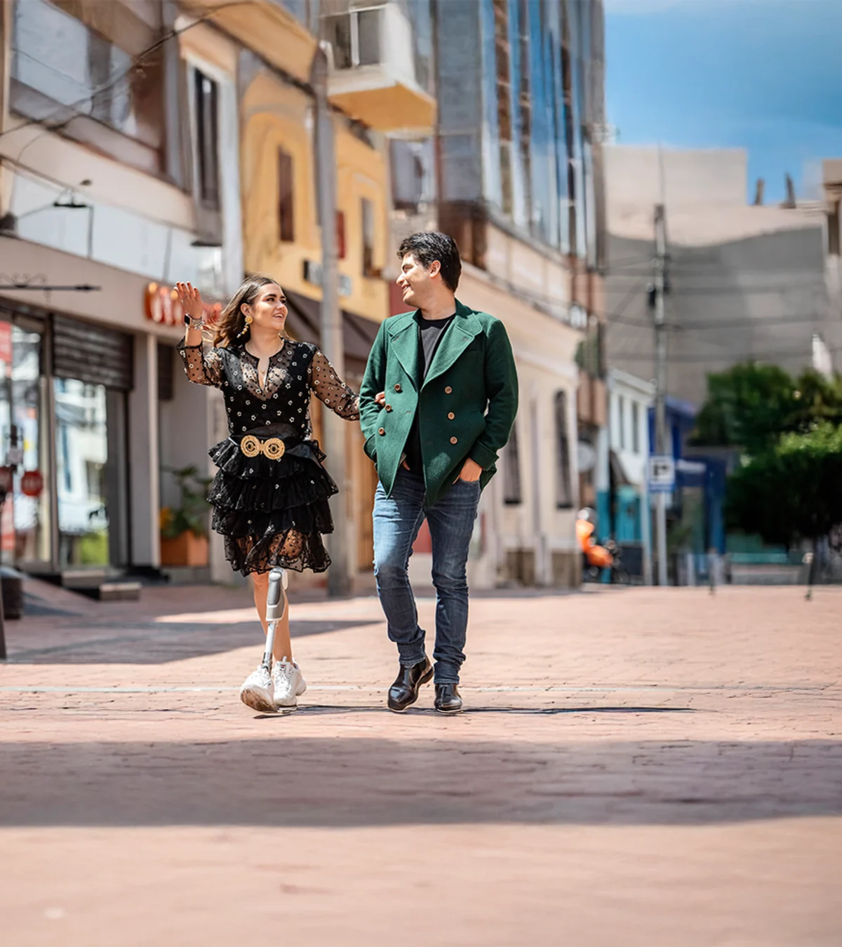A Dynion prosthetic leg user walks with a companion around an outdoor shopping mall