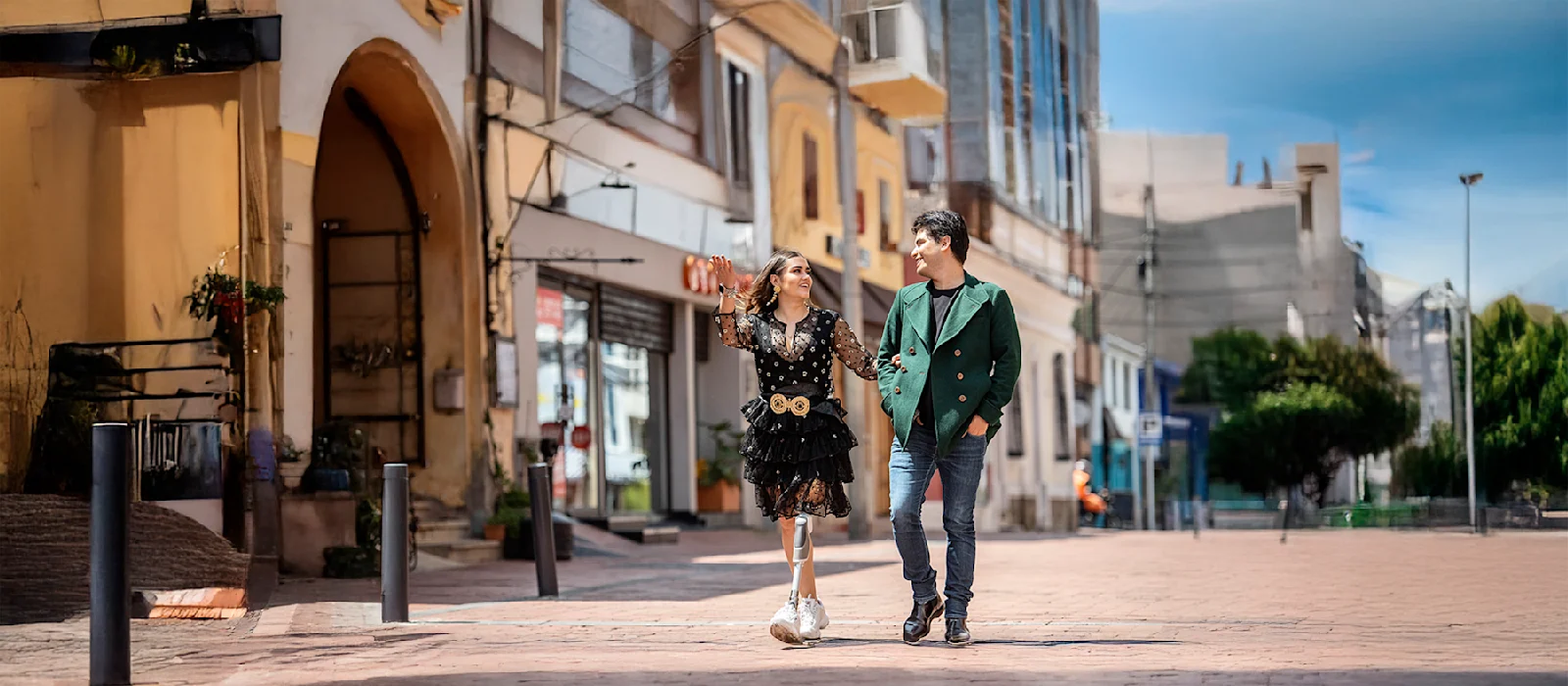 A Dynion prosthetic leg user walks with a companion around an outdoor shopping mall