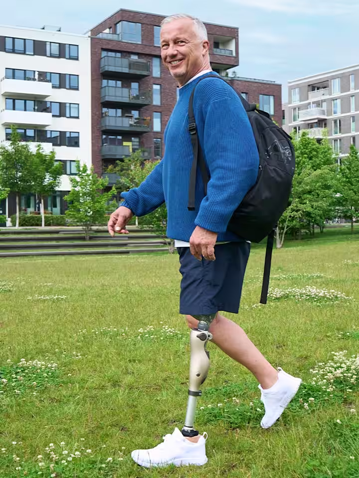 Un usuario protésico mayor caminando al aire libre con su rodilla controlada por microprocesador Ottobock Kenevo