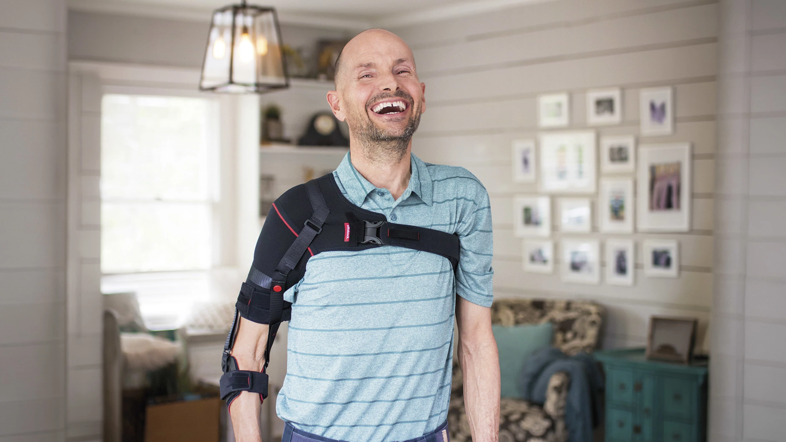 Un paziente con ortesi di spalla Omo Neurexa plus sorride mentre viene fotografato nel suo studio