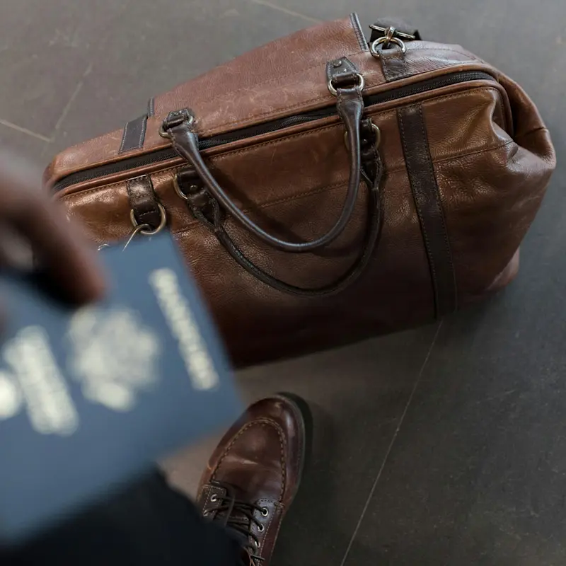 A suitcase on the ground as the owner puts away their passport