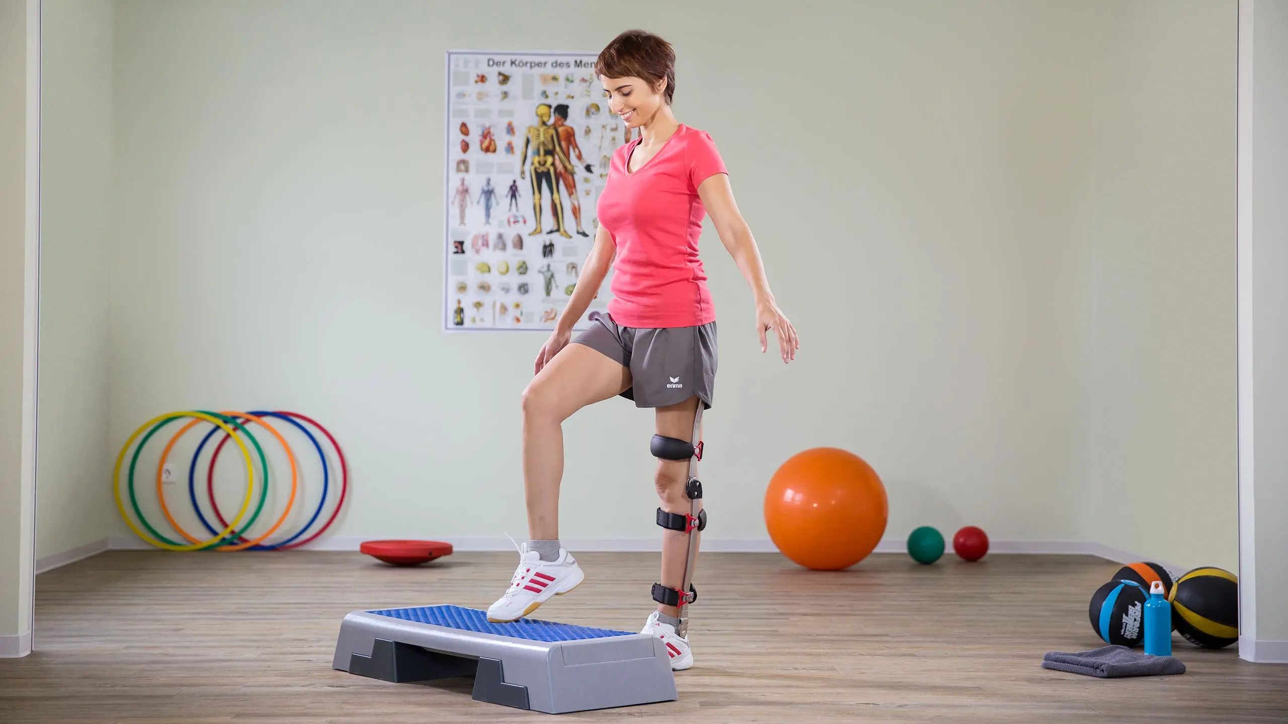 Una ragazza si allena in palestra su una pedana da step indossando sulla gamba sinistra una ortesi FreeWalk Ottobock