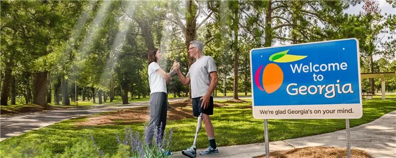 A prosthetic leg user greeting a Prosthetist on an outdoor trail