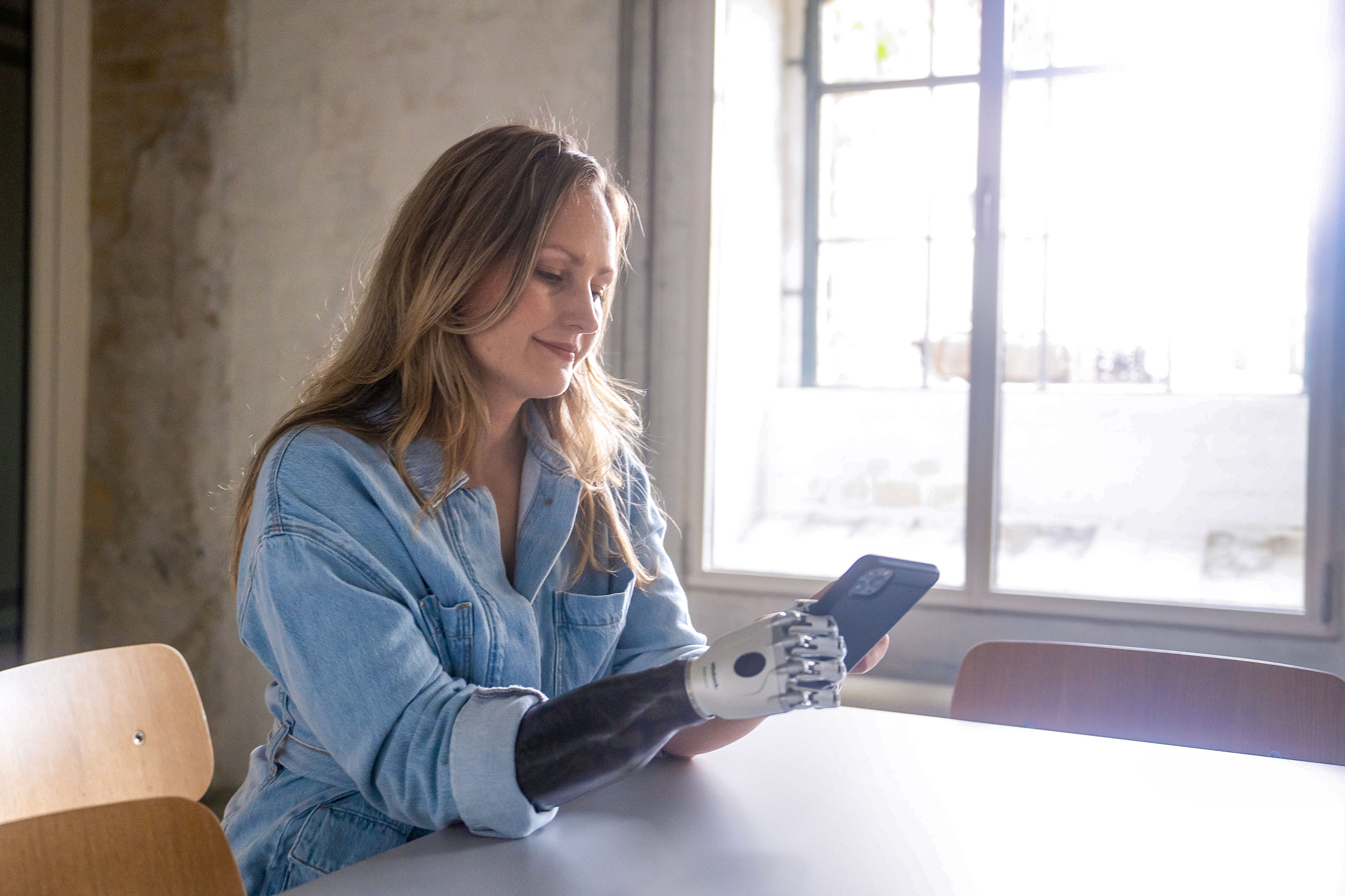 An upper limb amputee browsing on their smartphone with their prosthetic hand