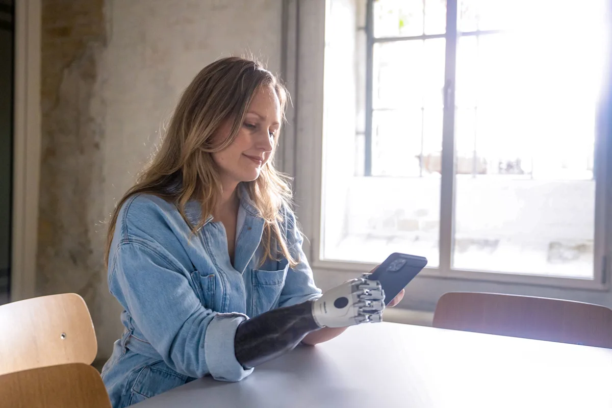 An upper limb amputee browsing on their smartphone with their prosthetic hand