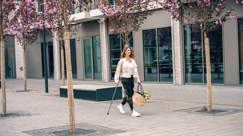 C-Brace bilateral Rodilla Tobillo Pie usuario ortésico Ayleen caminando a través de un centro comercial
