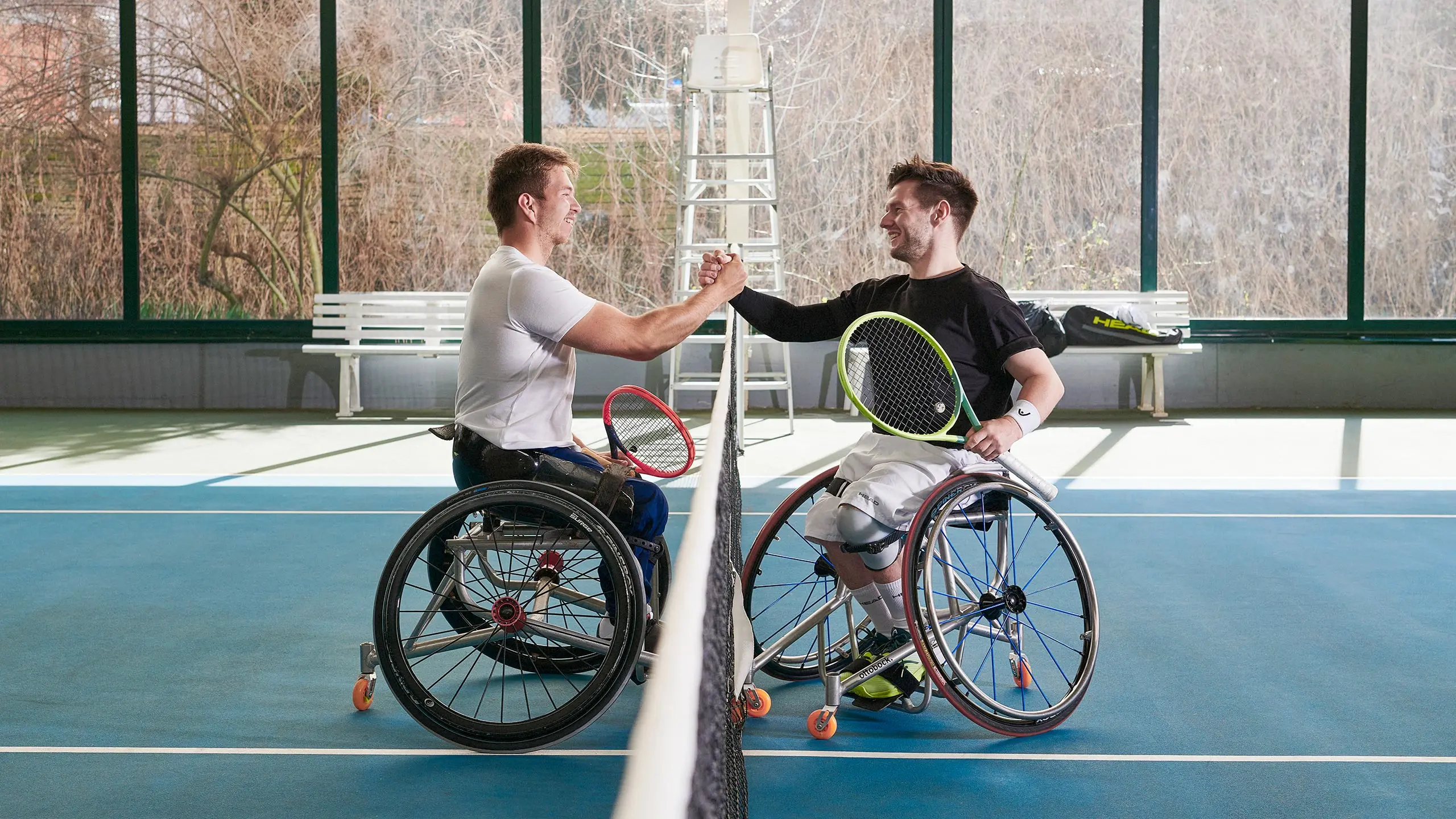 Due tennisti in carrozzina si stringono la mano a rete al termine di un incontro