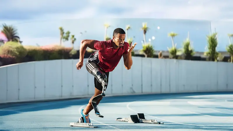 An adaptive athlete preparing to practice on an outdoor track with a prosthetic running blade