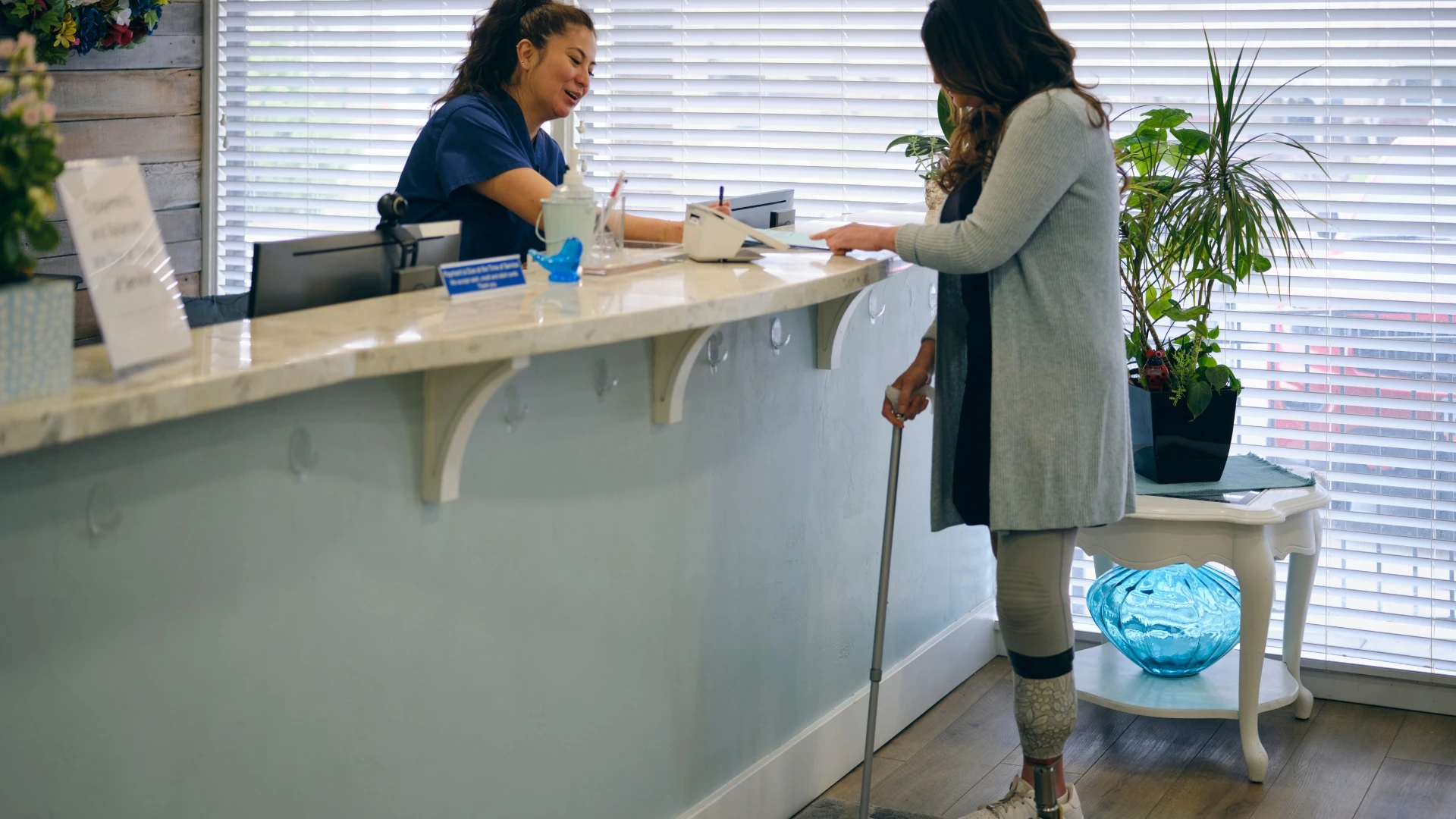A lower limb amputee at the patient care center's front desk making an appointment