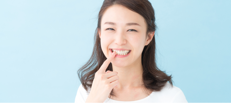 笑顔で歯を指さしている女性