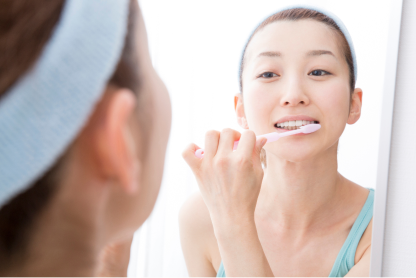 鏡を見ながら歯磨きをする女性