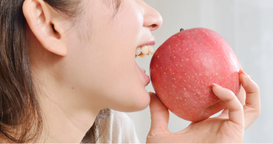 前歯でりんごを噛む女性