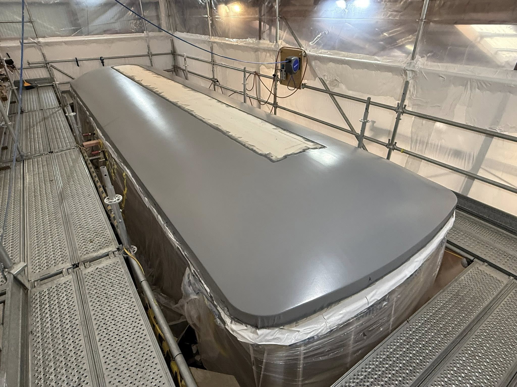 The fully stretched canvas is sized and  several coats of 2-part marine grade waterproof paint is applied until the surface is smooth enough to allow water run-off